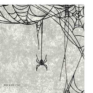 A decorative throw blanket featuring a black spider and intricate spiderwebs 