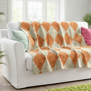 White sofa with a geometric patterned orange and beige throw blanket and colorful pillows.