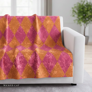 Patterned pink and orange blanket draped over a white sofa in a room with a plant.