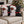 Two square throw pillows with a festive Christmas design featuring a Black man dressed as Santa Claus, sitting on a beige sofa in front of a blurred Christmas tree.