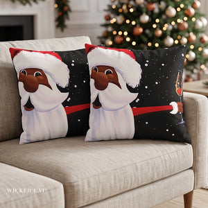 Two square throw pillows with a festive Christmas design featuring a Black man dressed as Santa Claus, sitting on a beige sofa in front of a blurred Christmas tree.