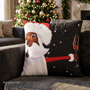 A square decorative throw pillow featuring a festive Christmas design, resting on a dark gray sofa in a decorated living room. The pillow displays a split design: one side shows a cartoon-style Black Santa Claus with a white beard and hat, and the other side is black with white snowflakes and a hand holding a champagne glass.