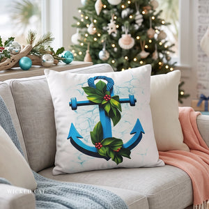 A square white throw pillow with a blue anchor and green holly design, styled on a light gray sofa in a cozy living room with a decorated Christmas tree in the background.