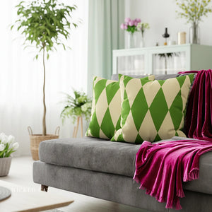 Gray sofa with green and white patterned cushions and a pink blanket in a bright living room.