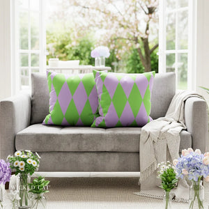 Gray sofa with green and purple patterned pillows in a bright room with flowers.