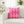 Pink diamond patterned pillow on a white couch with a blurred indoor background