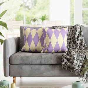 Gray sofa with purple and yellow patterned pillows and a plaid blanket in a bright room.
