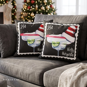 Two square throw pillows on a gray sofa featuring a Christmas-themed margarita design with a margarita glass, lime slices, red and white striped Santa hat, and the text '25¢' and 'Merry Margarita'.