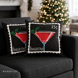 Two square throw pillows with a Christmas-themed 'Merry Martini' stamp design, styled on a dark gray sofa with a blurred Christmas tree in the background.