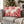 Two Christmas throw pillows with red peppermints on a grey couch in a living room decorated for the holidays.