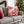 Christmas throw pillow with red peppermints on a grey couch in a living room decorated for the holidays.