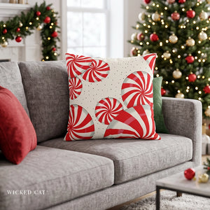 Christmas throw pillow with red peppermints on a grey couch in a living room decorated for the holidays.