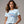 Woman wearing a light blue t-shirt with text design on a plain background