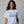 Woman wearing a light blue t-shirt with colorful text on a gray background