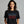 Woman wearing a black t-shirt with colorful text on a gray background