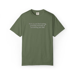Sage green t-shirt with 'Rain is just God crying, probably because of something  you did." embroidered text on a white background
