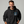 Man wearing a black hoodie with a skull design on a gray background