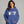 Woman wearing a blue hoodie with text, standing against a gray background