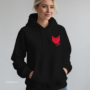 Person wearing a navy blue hoodie with embroidered 'Wicked Heart Women's' design on a plain background