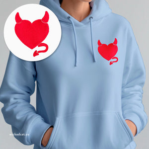 Person wearing a white hoodie with embroidered 'Wicked Heart Women's' design on a plain background