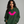 Woman wearing a green hoodie with a pink bat design on a gray background