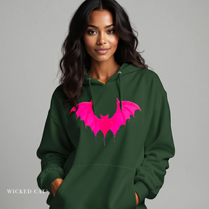 Woman wearing a green hoodie with a pink bat design on a gray background