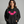Woman wearing a black hoodie with pink bat design on a gray background