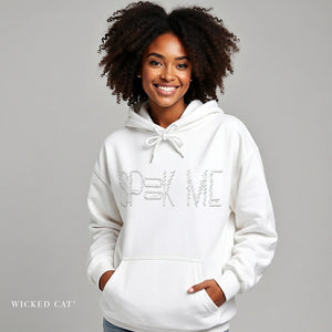 Woman wearing a white hoodie with text, standing against a gray background