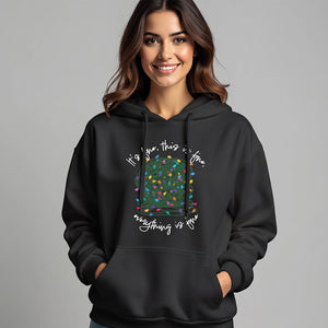 woman wearing a black sweatshirt hoodie with a graphic of a ball of tangled Christmas lights and text that says 'It's fine, this is fine, everything is fine'.
