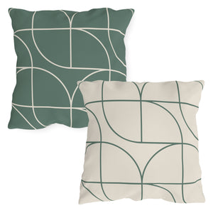 Two square outdoor throw pillows with a geometric Art Deco design. One in green on a white background and the other in white on a green background, both with a visible concealed zipper.