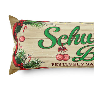 A rectangular decorative pillow with a rustic wood-plank background and festive Christmas graphics, including green script text reading 'Schw.