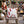 A square white throw pillow with a red candy cane pattern, displayed on a rustic wooden rocking chair in a festive outdoor holiday setting with a fire pit, nutcracker, and Christmas lights.