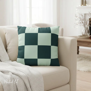 Checkered green and white pillow on a beige sofa in a living room setting.