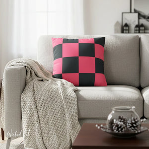 Checkered pink and black pillow on a gray sofa with a blanket and decorative items.