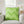 Green chevron patterned pillow on a gray chair with a blurred background