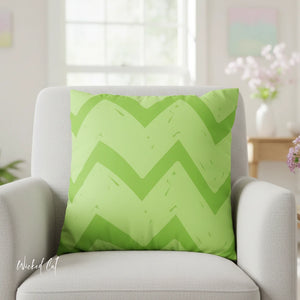 Green chevron patterned pillow on a gray chair with a blurred background