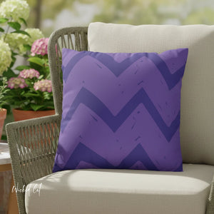 Purple zigzag patterned pillow on a beige chair with outdoor plants in the background