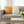 Gray sofa with decorative pillows featuring honeycomb and bee patterns, next to a wooden coffee table with tulips.