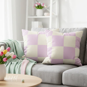 Gray sofa with checkered purple and white pillows, surrounded by tulips and a green blanket.