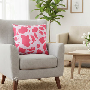 Gray armchair with a pink cow print pillow in a living room setting.
