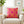 Pink pillow with yellow geometric pattern on a beige armchair in a living room setting.