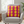 Pink pillow with yellow circles on a gray armchair in a room with a plant and window.