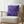 Purple zigzag patterned pillow on a white chair with a blurred background