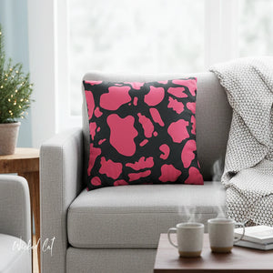 Pink and black abstract patterned pillow on a gray sofa with a coffee table in the foreground