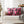 Pink and black patterned pillows on a white couch with a blurred festive background