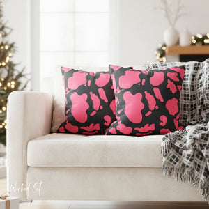 Pink and black patterned pillows on a white couch with a blurred festive background