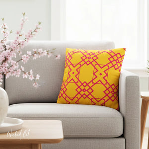 Yellow pillow with pink geometric pattern on a gray sofa in a living room setting.