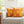 Yellow and pink patterned pillows on a white couch with a blurred background