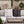 Two decorative throw pillows with a repeating 'HO HO HO' candy cane pattern, styled on a white outdoor sectional sofa. One pillow is white with red lettering, and the other is black with red lettering.