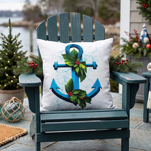 A square white outdoor throw pillow featuring a blue anchor design decorated with green holly leaves and red berries, displayed on a distressed teal Adirondack chair in a holiday-themed outdoor setting.